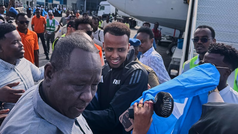 Referee Omar Artan, center, who was denied entry to the United States, is welcomed by...
